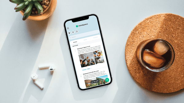 Mindspace journal app showing entries on iPhone with AirPods and coffee