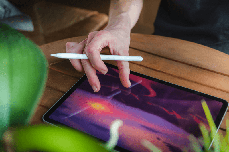 A hand holding an Apple Pencil over an iPad, ready to handwrite and sketch a journal entry