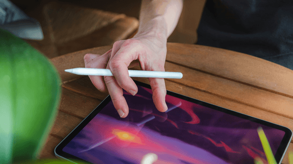 A hand holding an Apple Pencil over an iPad, ready to handwrite and sketch a journal entry